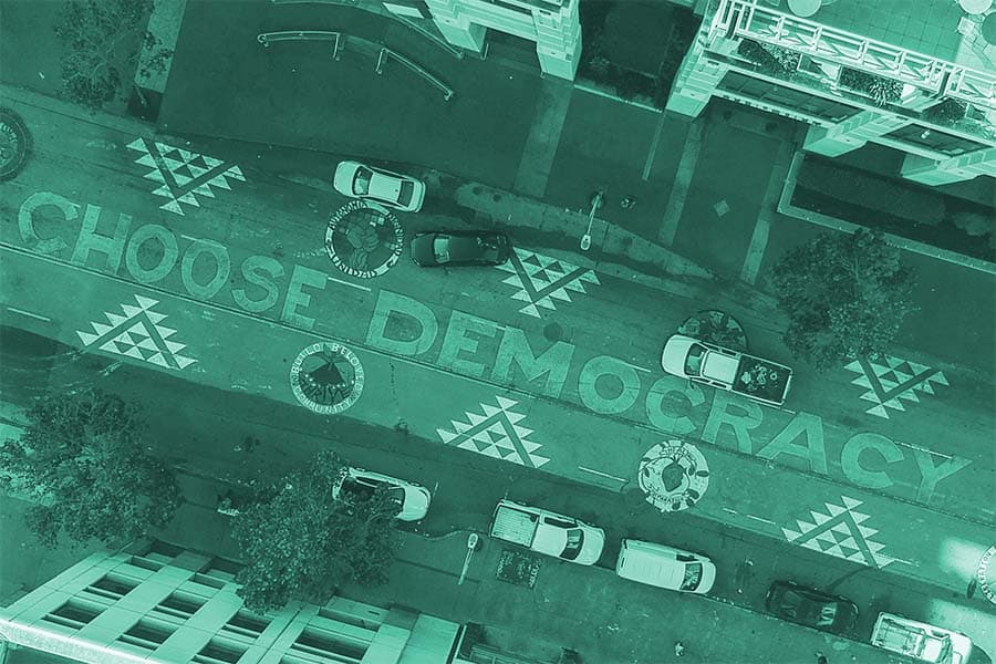 A placeholder image of an overhead image of a street with paint reading Choose Democracy 