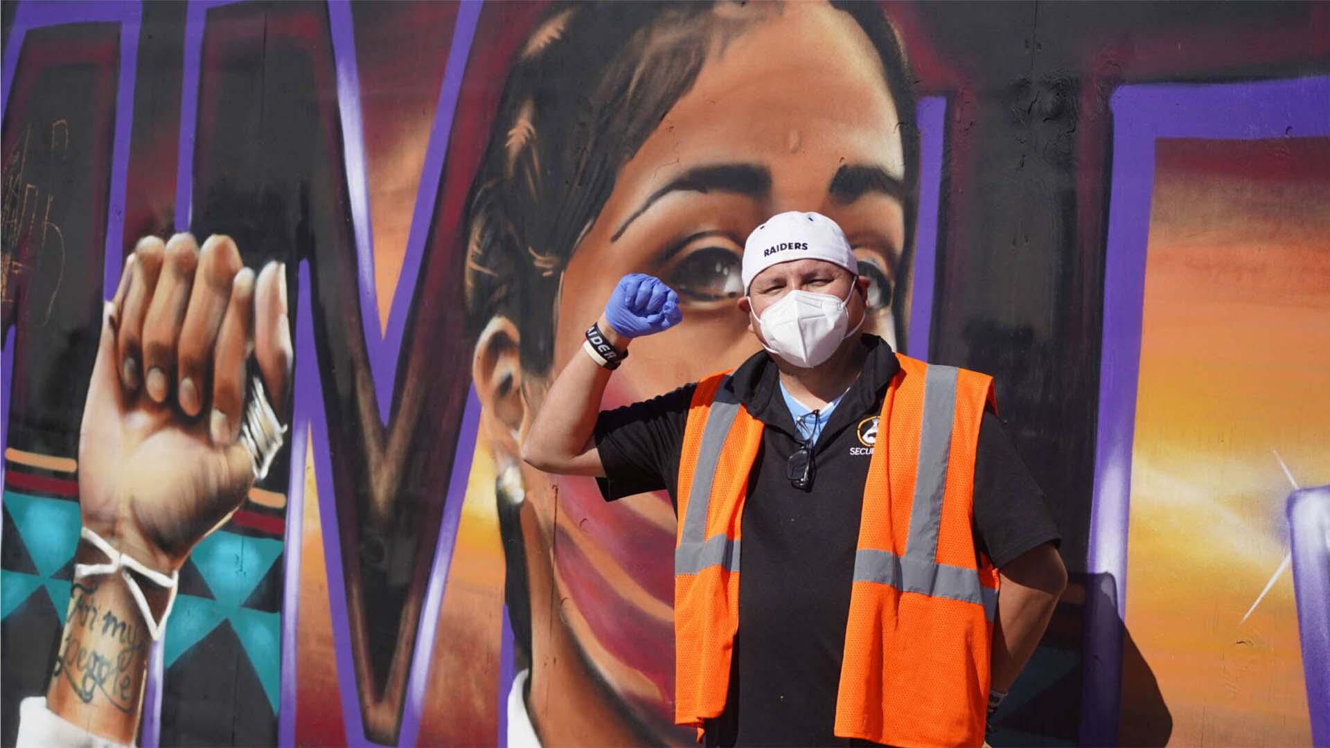 Man raising a fist in front of a mural