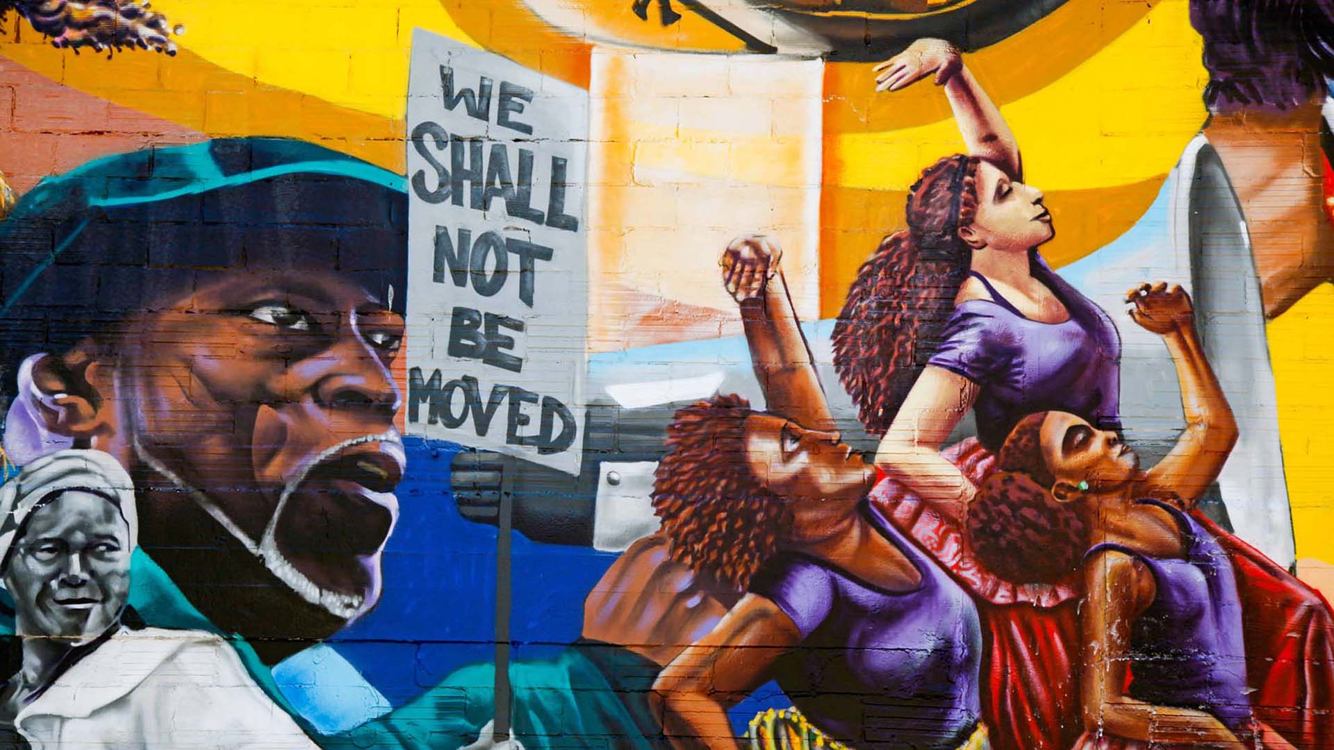 Mural depicting women dancing and an activist with a megaphone