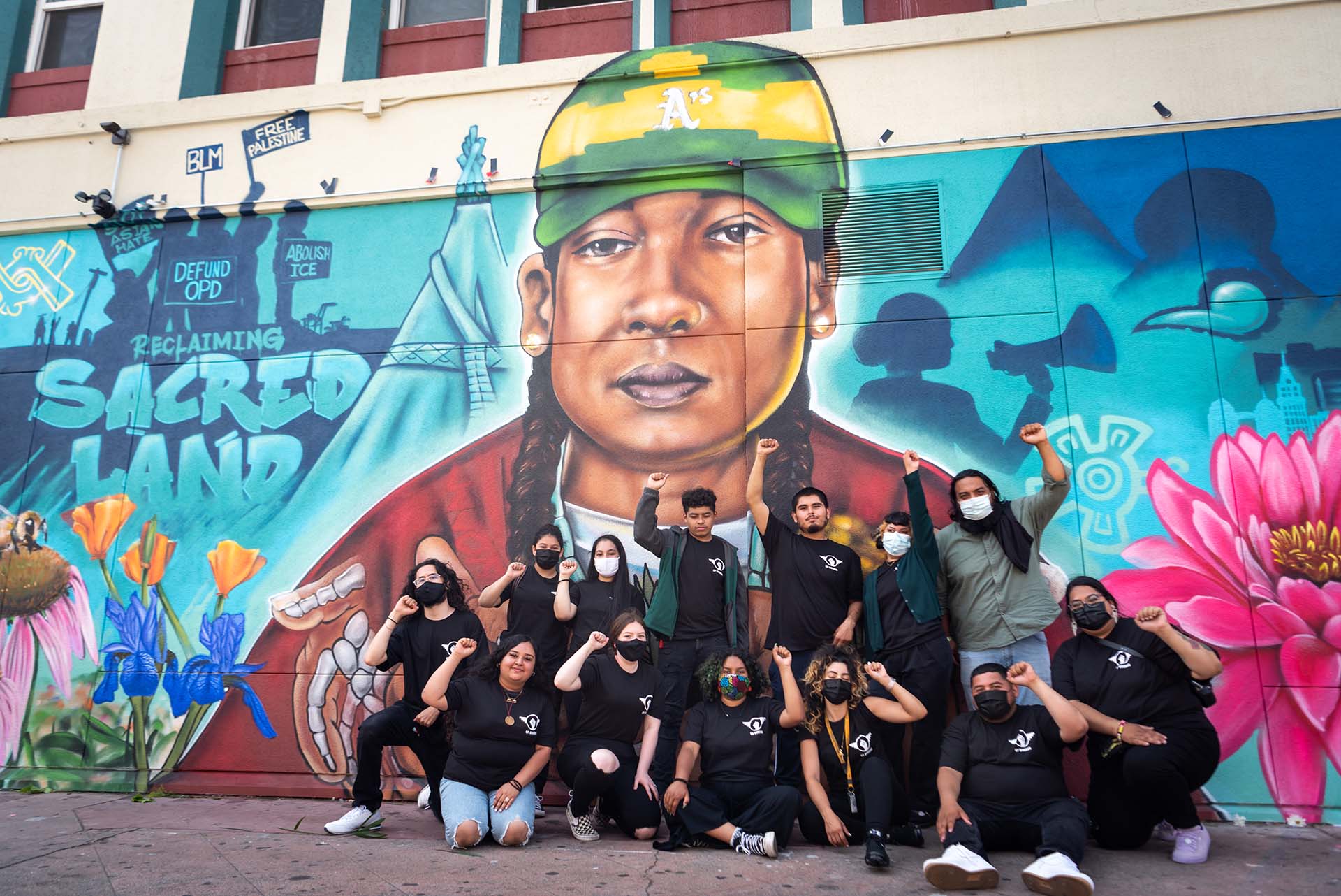 A group of people with fists raised in front of a large mural