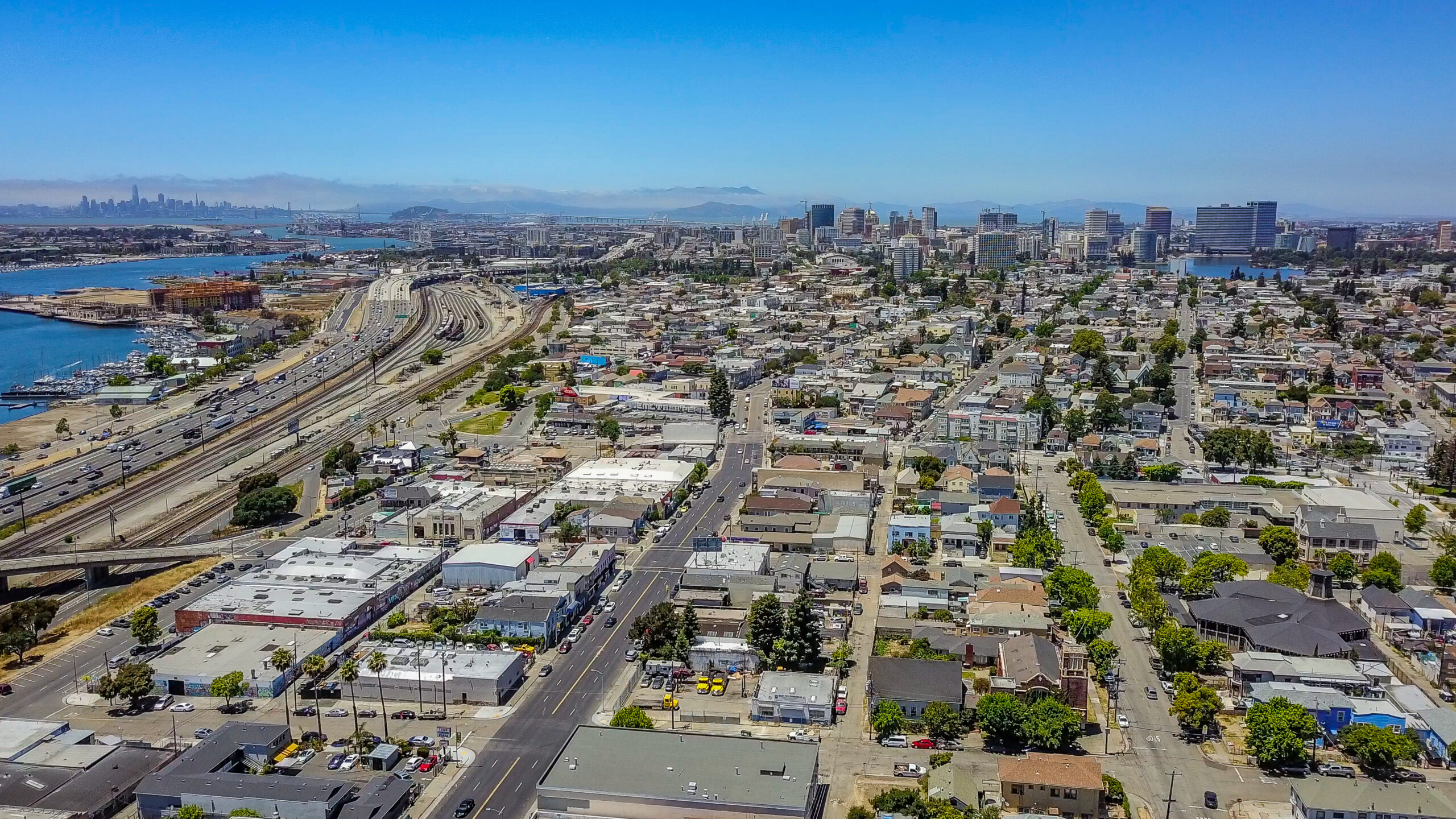 Aerial view of Oakland with San Francisco across the Bay. City skyline for both cities can be seen on the horizon.The Embarcadero area and Oakland Harbor, 880 Freeway and bart route in view.